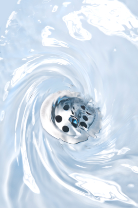 Swirling light blue water flowing down a silver drain