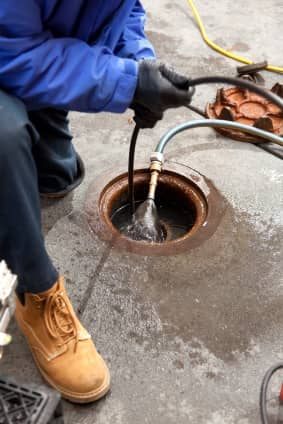Man in work boots inspecting sewer line with sewer scope camera