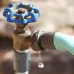 Leaking outdoor spigot with blue handle leaking at hose connection