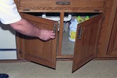 a man opening a small wooden cabinet
