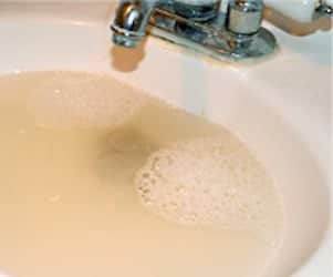 A clogged bathroom sink with dirty water in it.