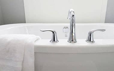 white bathtub with white towel hanging on it
