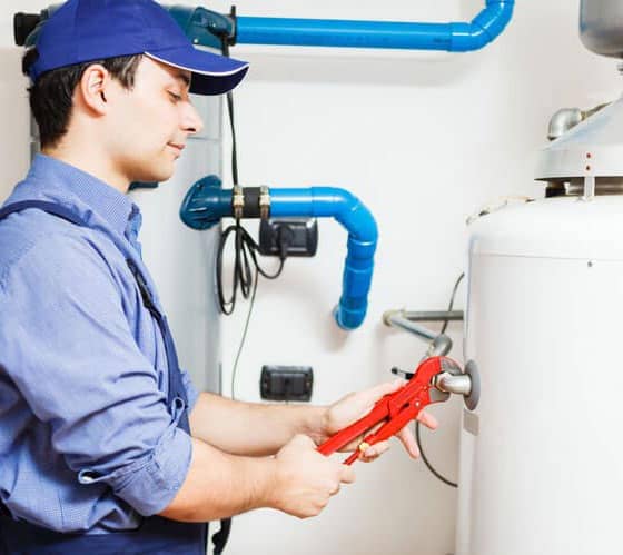 A repairman with a red wrench fixes a 50-gallon hot water heater