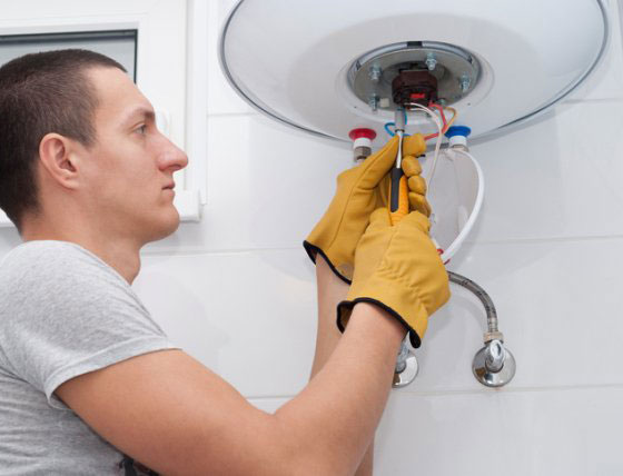man using tools to replace a water heater