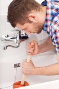 Plumber unclogging a bathtub drain.