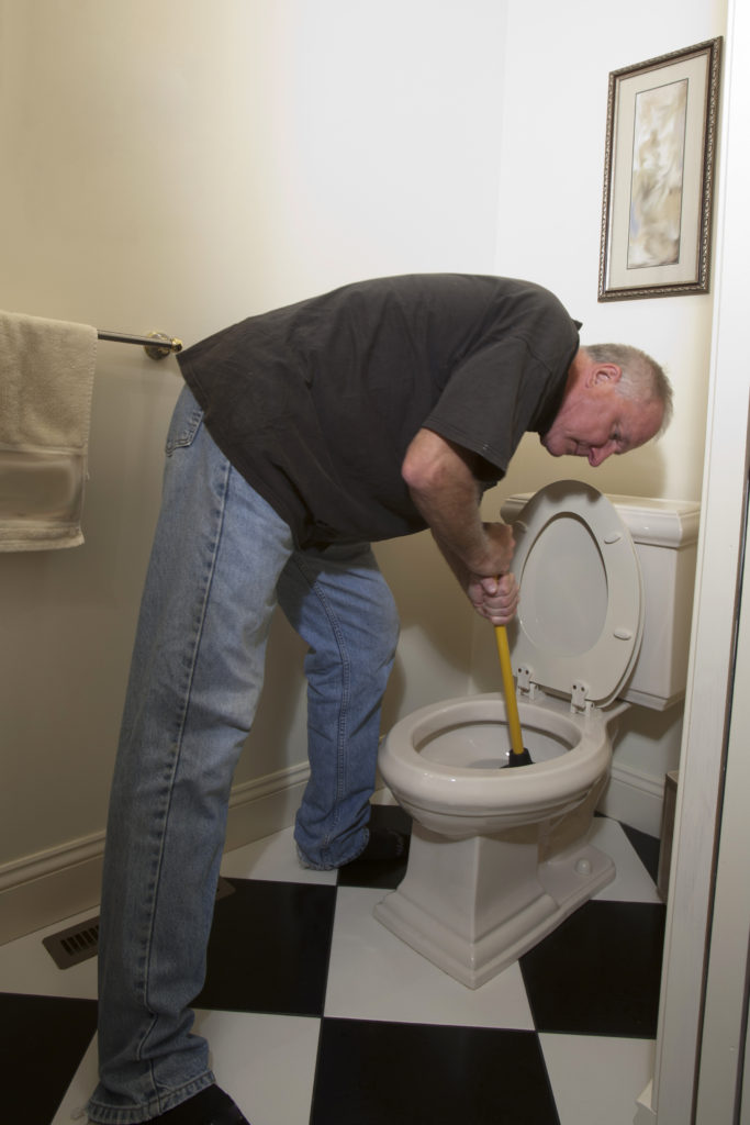 Man in with plunger fixing blocked toiler
