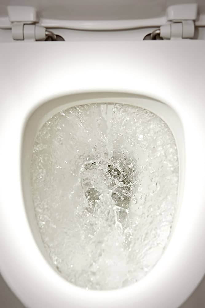 A toilet is clogged and filling to the top with clean water