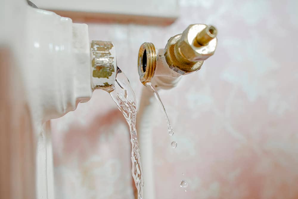 A pipe has broken in a bathroom and is leaking water from the break