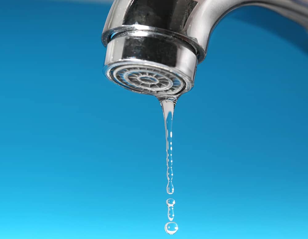 A kitchen faucet is leaking drips of water