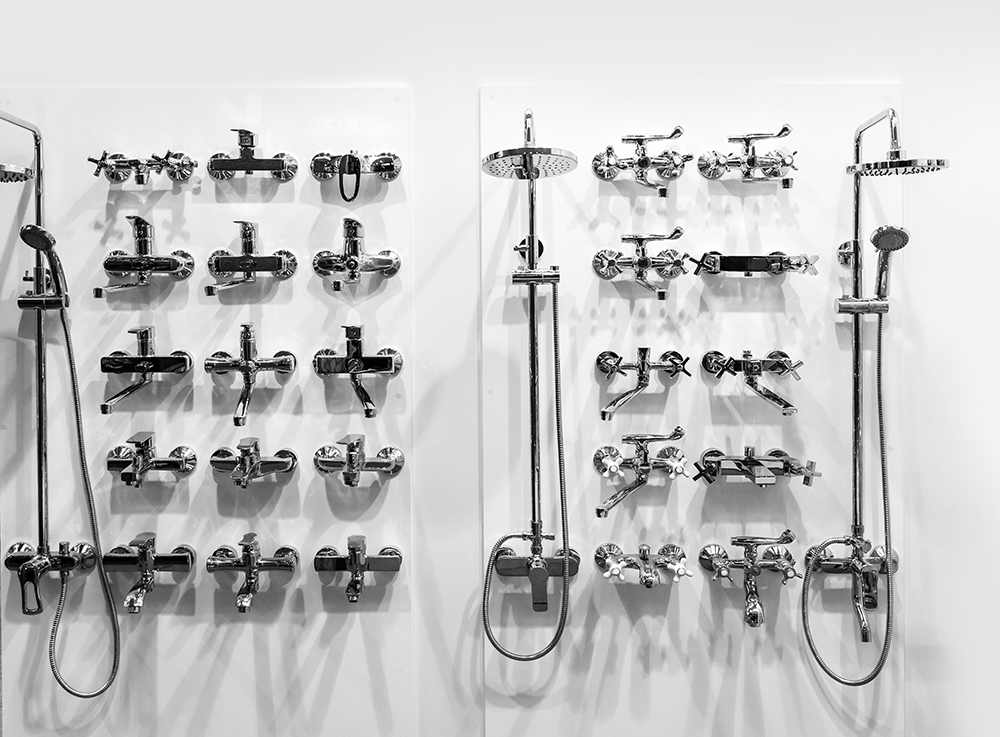A wall of a display of new chrome plumbing fixtures with shower heads and faucets