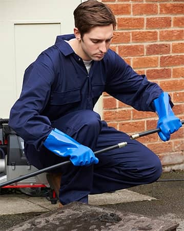 A Simply Sewers plumber cleans out a sewer line from an access drain in the yard.