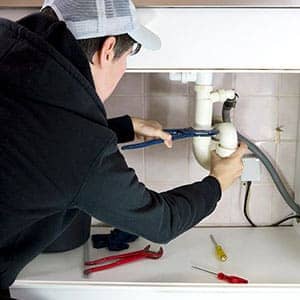 plumber repairing a choked-up drain with pliers