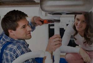 woman watching plumber fixing a sink drain