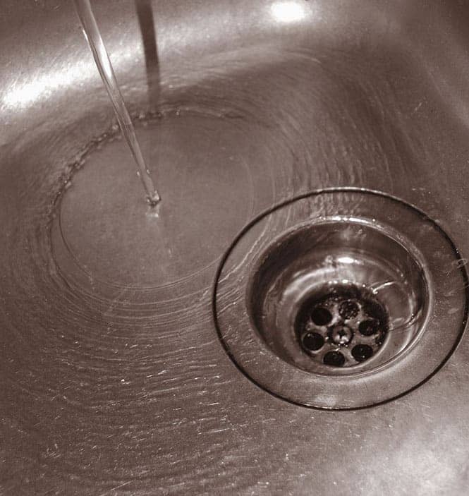 stream of water flowing down in the stainless water drain
