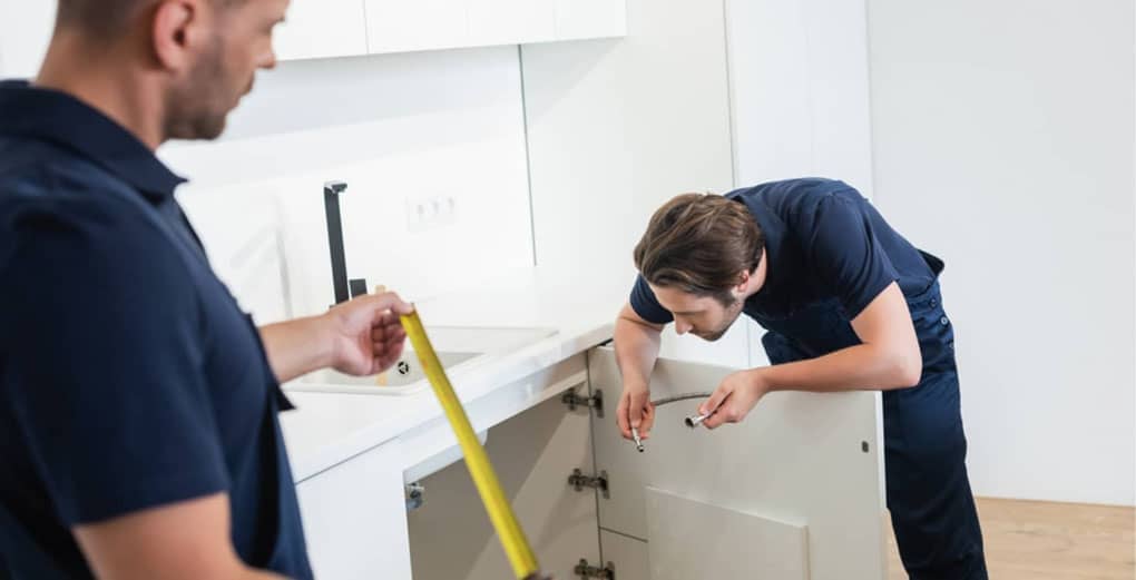 worker holding measuring tape near plumber